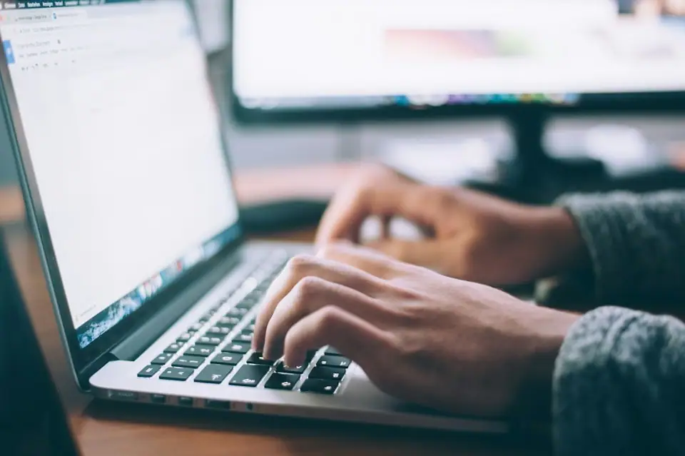 Hands typing on a laptop while searching for work